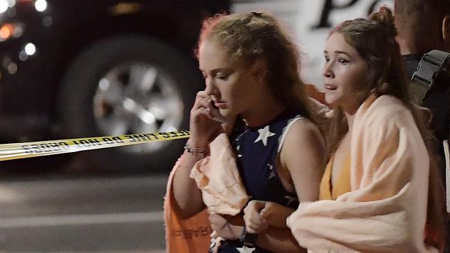 People walk away from the scene Thursday, Nov. 8, 2018, in Thousand Oaks, Calif. where a gunman opened fire Wednesday inside a country dance bar crowded with hundreds of people on "college night," wounding 11 people including a deputy who rushed to the scene. Ventura County sheriff's spokesman says gunman is dead inside the bar. (AP Photo/Mark J. Terrill)