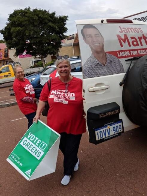 A Labor volunteer with Greens placards.