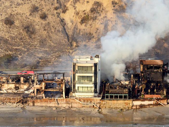 TOPSHOT - In this aerial view taken from a helicopter, burned homes are seen from above during the Palisades fire in Malibu, Los Angeles county, California on January 9, 2025. Massive wildfires that engulfed whole neighborhoods and displaced thousands in Los Angeles remained totally uncontained January 9, 2025, authorities said, as US National Guard soldiers readied to hit the streets to help quell disorder. Swaths of the United States' second-largest city lay in ruins, with smoke blanketing the sky and an acrid smell pervading almost every building. (Photo by JOSH EDELSON / AFP)