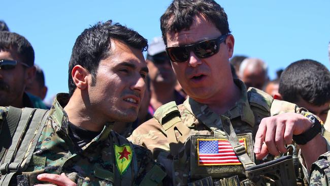 A US officer with a fighter from the Kurdish People's Protection Units (YPG) at the site of Turkish air strikes near northeastern Syrian Kurdish town of Derik. Picture: AFP.