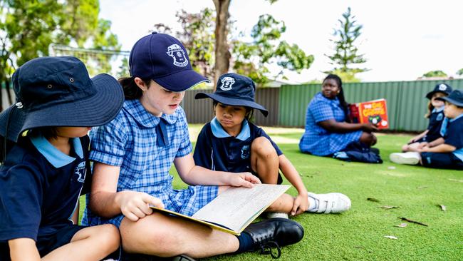 St Patrick's School students reading outdoors.