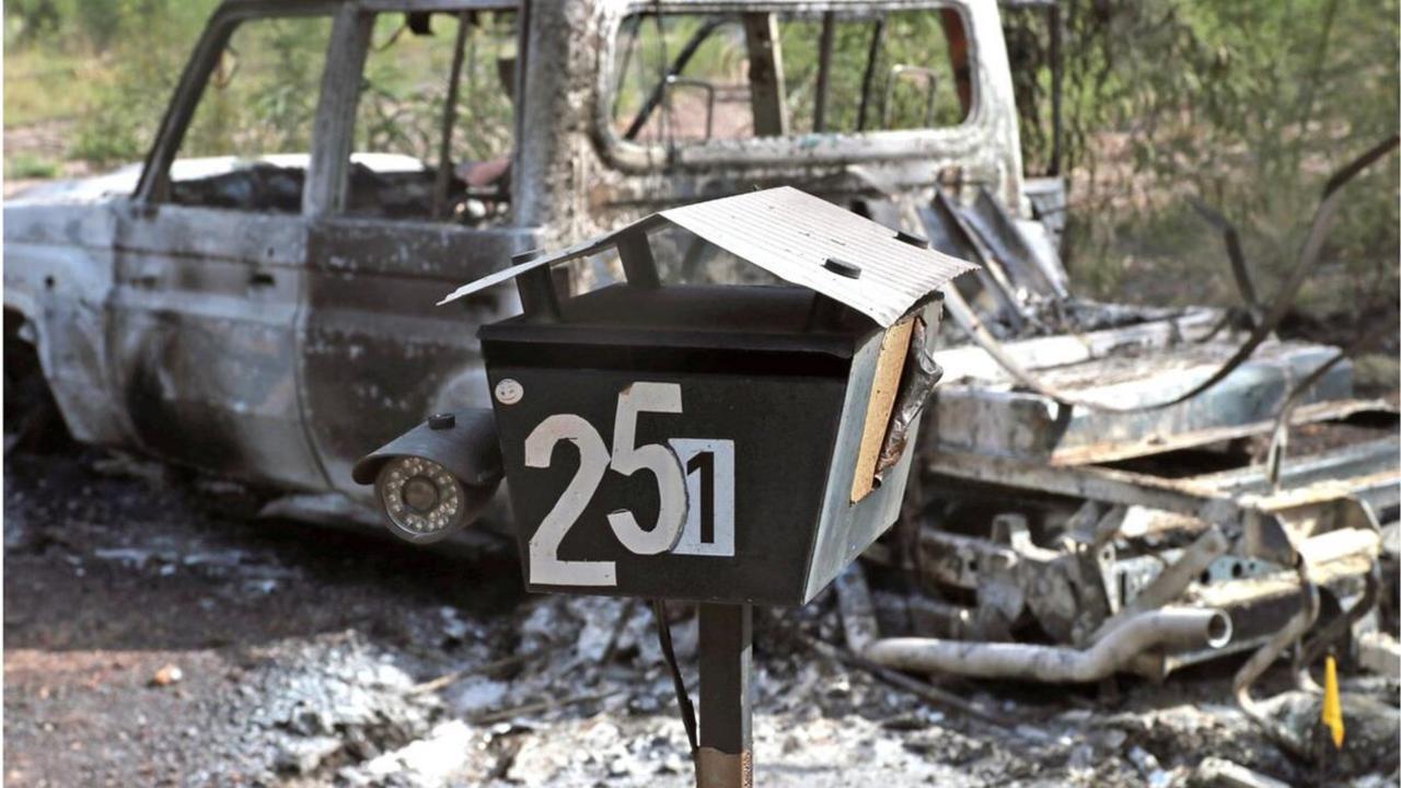 The burnt out police vehicle the Trains set on fire with their letterbox - which depicts a security camera - in the foreground.
