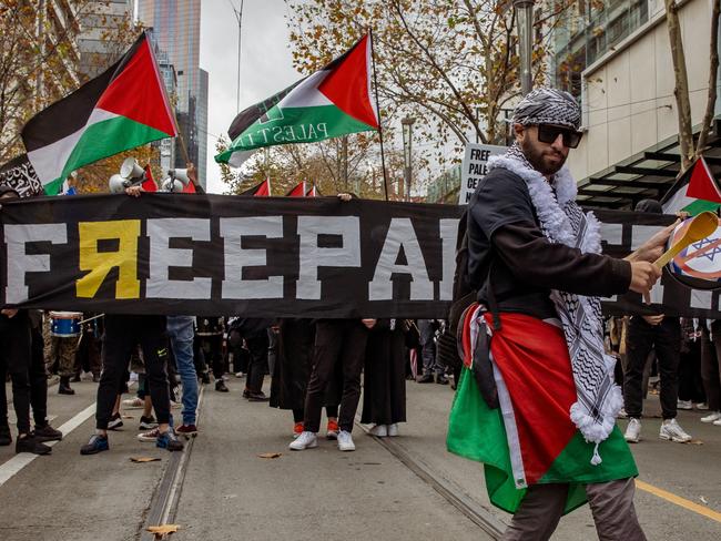 MELBOURNE, AUSTRALIA - NewsWire Photos - JUNE 2, 2024:  Pro Palestine supporter plays the drum with a sticker of Israel crossed out, in Melbourne Australia Picture: NewsWire / Tamati Smith
