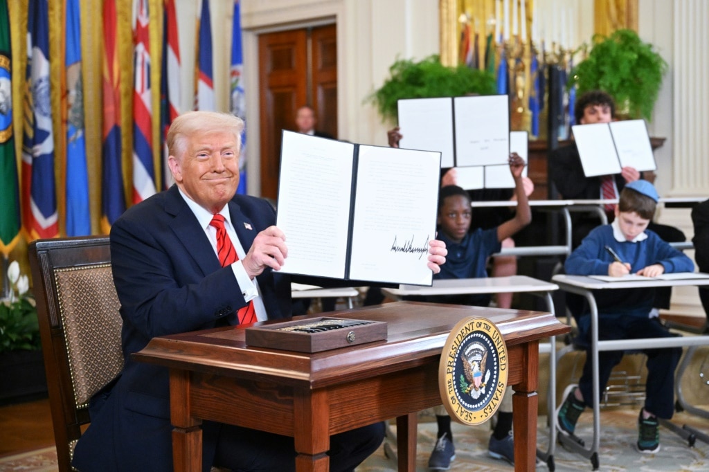 US President Donald Trump holds up an executive order dismantling the Education Department after signing it in the East Room of the White House