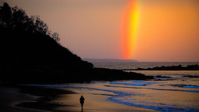 A lone walker enjoys a rainbow at sunset on Narrawallee Beach at Mollymook on the NSW south coast this month. Picture: AFP