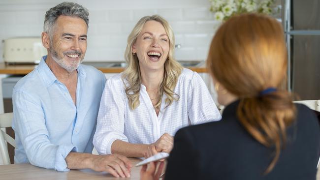 Happy mature couple meeting investments and financial advisor at home. They are happy and smiling. The agent is holding a digital tablet.  Planner advice generic