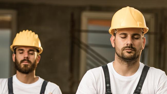 Group of construction workers exercising Yoga in Lotus position during a break at balcony.