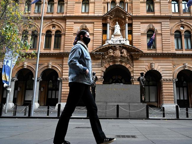 A woman wearing a face mask walks through a quiet Martin Place in Sydney on July 27, 2021, as around half of Australia's 25 million largely unvaccinated residents are currently under stay-at-home orders. (Photo by Saeed KHAN / AFP)