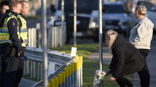 People bring flowers to the scene of an overnight fatal hit and run on Thompsons Rd in Cranbourne North. Picture: Andrew Henshaw.