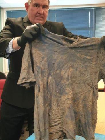 Clothes, shoes and a leg plate were found near the human remains off Keefton Road on the outskirts of Gympie. Detective Inspector Gary Pettifort holds the shirt up.