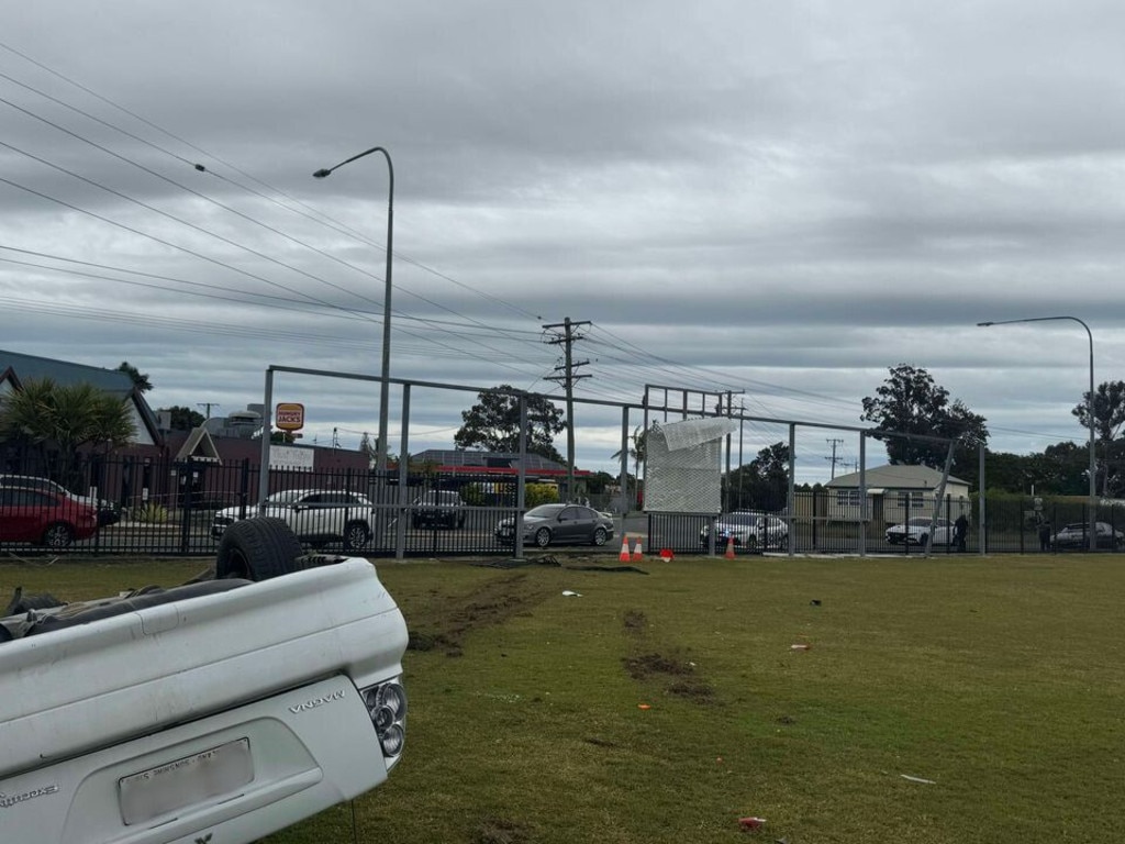 A woman driving a white car in Bundaberg smashed through a fence and flipped onto its roof before she was arrested by police. Photo: Clint Davies.