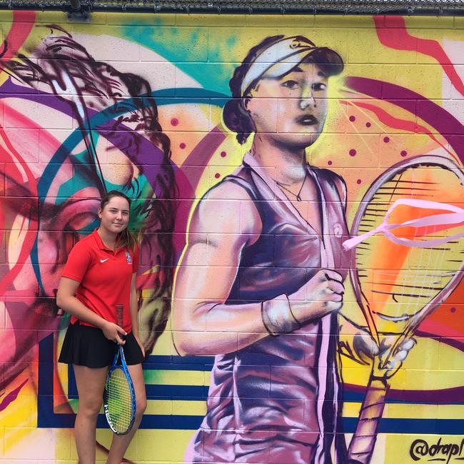 Kelvin Grove State High School tennis players Sydney Stone in front of the Ashleigh Barty mural at the Queensland Tennis Centre.