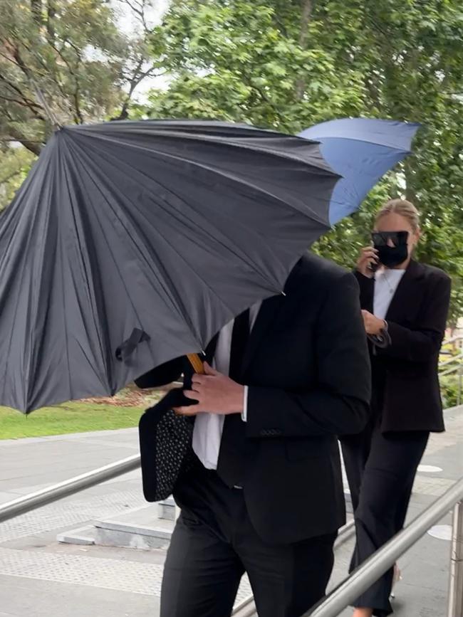 Michael Phillip Touzell (black umbrella) and his fiance Rachel Katherine Keith (face mask) on Tuesday. Picture: Canterbury-Bankstown Express