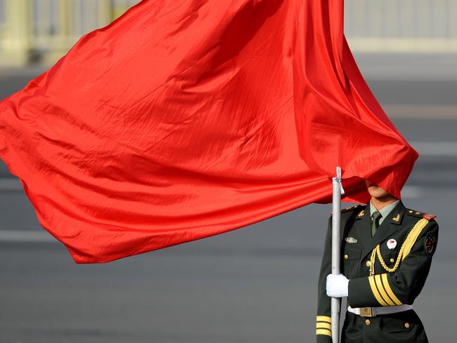 The winds blows a red flag on a Chinese honour guard's face as he stands guard before Sri Lankan President Mahinda Rajapaksa and Chinese President Xi Jinping. Picture: AFP