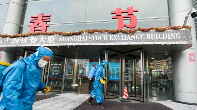 Medical workers spray antiseptic outside the Shanghai Stock Exchange Building. Picture: Getty Images