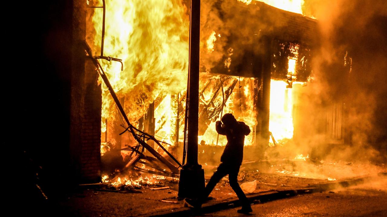 A protester outside a burning building in Minneapolis. Picture: Chandan Khanna / AFP