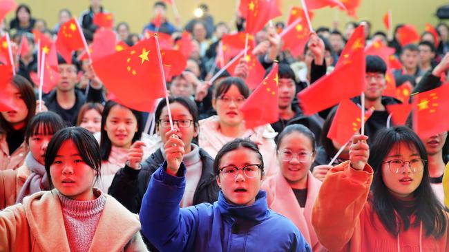 Students waving flags at Huaibei Normal University in Huaibei in China's eastern Anhui province as they watch live coverage of a speech by President Xi Jinping on December 18.