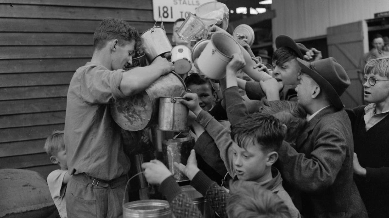 Boys line up to get a drink of fresh milk from the Ekka’s cows in 1949.