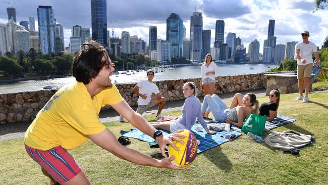 Clayton Sefo (left), Mark Nicolaidis (2nd from left), Indi Hawkins (2nd from right) and Lewis Begg (right) are seen passing a football as they have a picnic with friends at the Kangaroo Point Cliffs in Brisbane on Saturday. (AAP Image/Darren England)