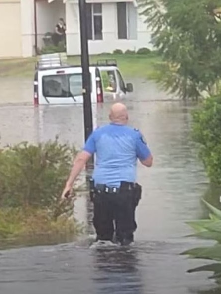 A police officer walking through knee deep water after flooding. (Facebook: Toddy White)