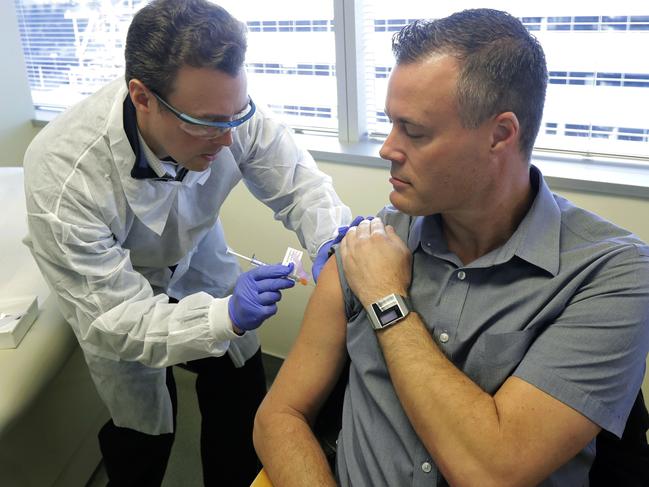 Pharmacist Michael Witte, left, gives Neal Browning, right, a shot in the first-stage safety study clinical trial of a potential vaccine for COVID-19, the disease caused by the new coronavirus Monday, March 16, 2020, at the Kaiser Permanente Washington Health Research Institute in Seattle. Browning is the second patient to receive the shot in the study. (AP Photo/Ted S. Warren)