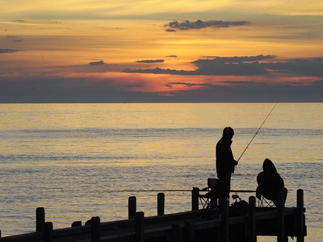 Two fisherman enjoy the sunset at the boat ramp jetty at the base Oliver's Hill.