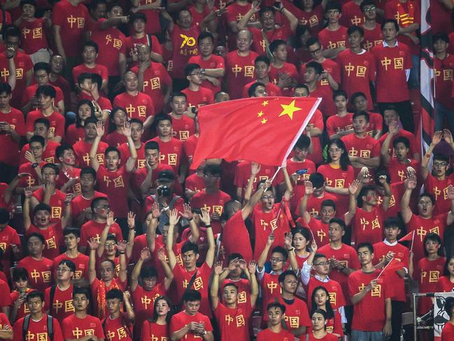 (FILES) This file photo taken on October 10, 2019 shows a fan waving the Chinese national flag as others cheer during the World Cup 2022 qualifier football match between China and Guam in Guangzhou. - The coronavirus exposes an ignorance of China's lucrative sports market and poor contingency planning, experts say, after Formula One became the most high-profile casualty of a mass pullout from the country. (Photo by STR / AFP) / - China OUT / TO GO WITH China-health-virus-sport,ANALYSIS by Peter STEBBINGS