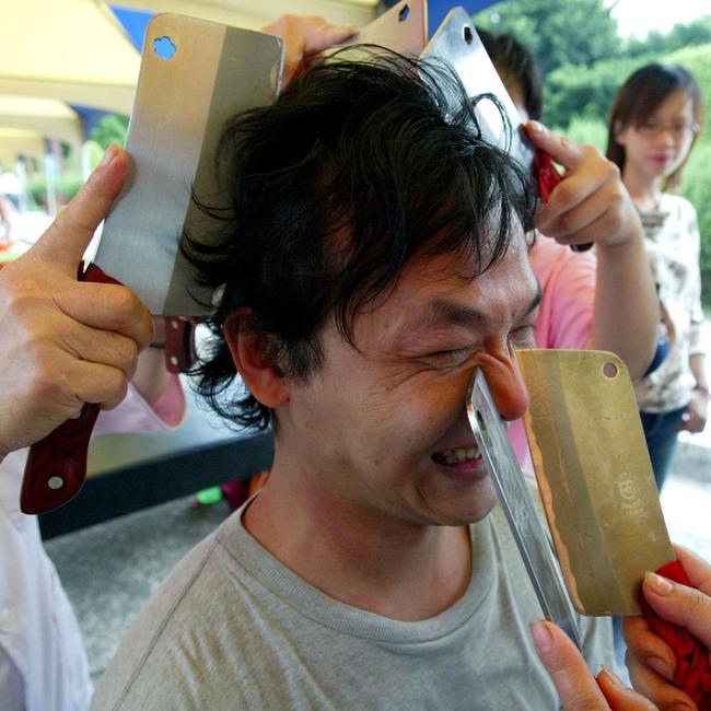 A man cringes as he receives a "knife therapy" massage. Picture: Steven Wang.