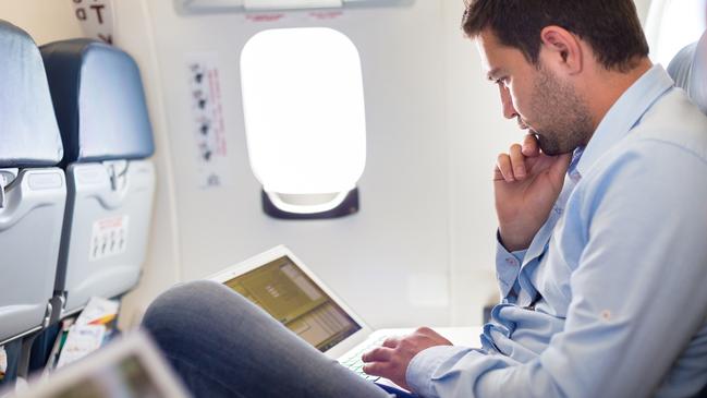 Casually dressed middle aged man working on laptop in aircraft cabin during his business travel. Photo: istock