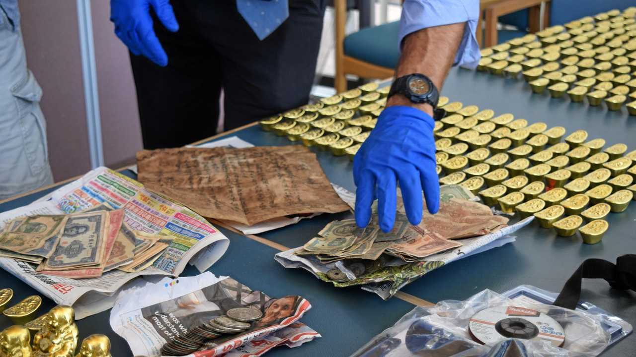 Fake gold Buddha statues, ingots, currency, coins and a map seized by police are alleged to have been used to scam people. Picture: Chloe Lyons