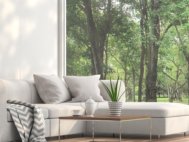 Minimal sofa located at the window 3d render.The Rooms have wooden floors and white wall.furnished with white fabric furniture.There are large frameless window looking out to see the garden view.