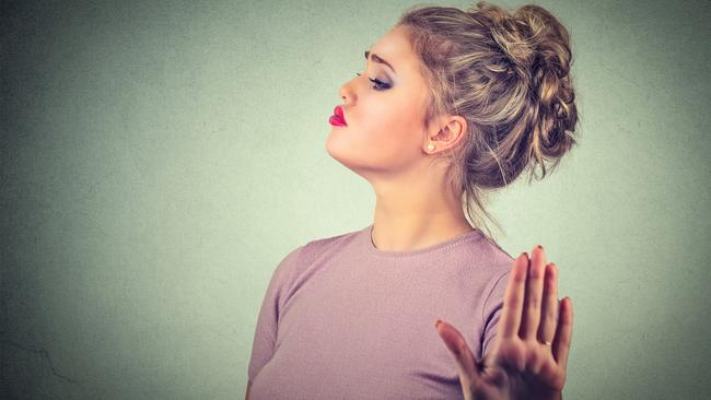 Snobby young annoyed angry woman with bad attitude giving talk to hand gesture with palm outward isolated grey wall background. Negative human emotion face expression feeling body language