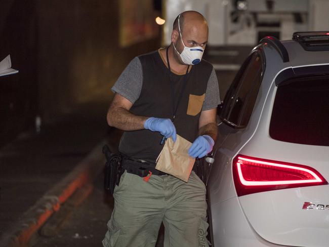 A police officer with a package next to an Audi in Docklands. Picture: Jason Edwards