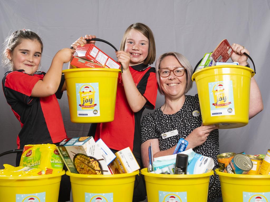 Sacred Heart Primary School students Amiya Diedrich (left) and Ivy Goodman give hamper buckets the school collected to Lyndal Hagin of YellowBridge Queensland after the awards presentation and Yr 6 graduation, Friday, December 2, 2022. Picture: Kevin Farmer