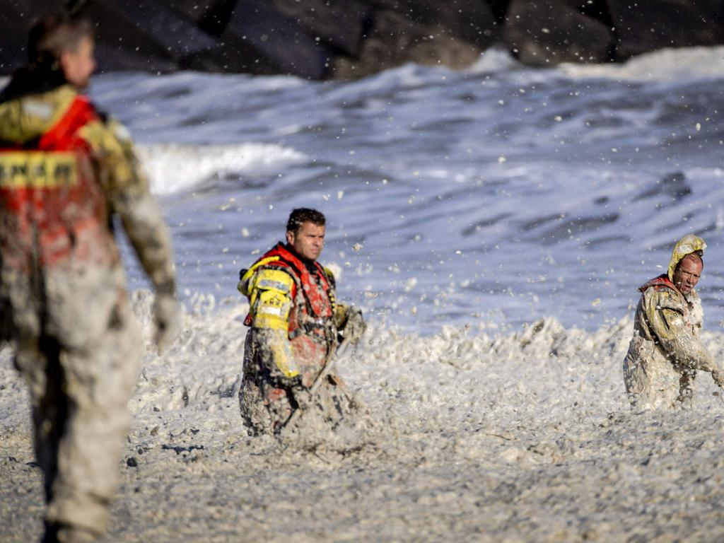 Rescue workers stand in rough waters during the search.