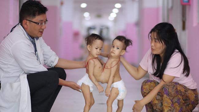 Nima and Dawa with paediatric surgeon Dr Karma Sherub and mum Bhumchu in the Bhutan hospital ward they've spent most of their lives in. Picture: Alex Coppel