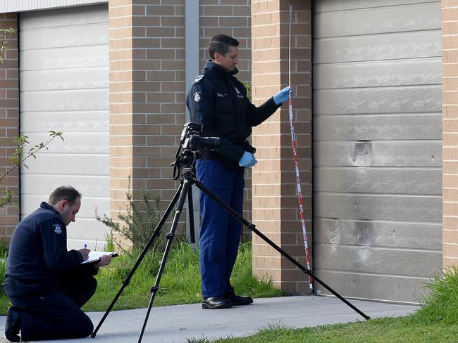 Ballistics experts review the bullet and pellet holes in the roller door of the Keysborough home after the fatal shooting. Picture: Nicole Garmston