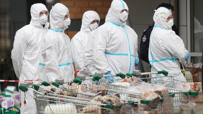 Firefighters in protective suits deliver food to the Towers in North Melbourne. Picture: David Crosling.