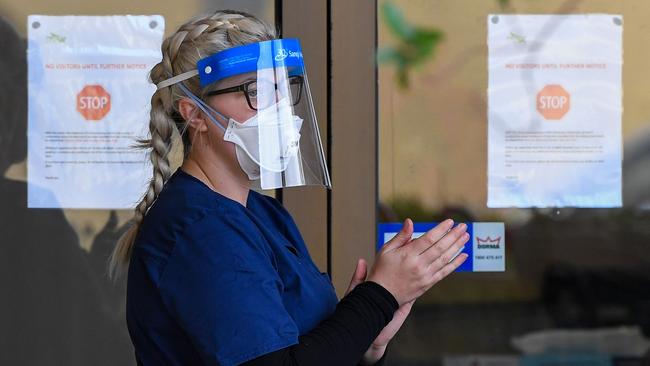 A staff member sanitises her hands outside the Menarock Life aged care facility.