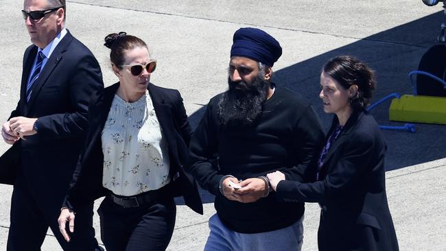 Queensland Police officers and detectives escort Rajwinder Singh from a chartered jet to a waiting police car at Cairns Airport after being extradited from New Delhi to Cairns via Melbourne. Picture: Brendan Radke