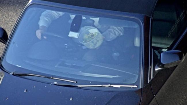 This man is driving with one hand and enjoying a meal with the other while motoring along a road at high speed.