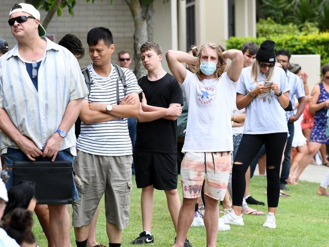 People are seen in long queues outside the Centrelink office in Southport on the Gold Coast, Monday, March 23, 2020. Centrelink offices around Australia have been inundated with people attempting to register for the Jobseeker allowance in the wake of business closures due to the COVID-19 pandemic.  (AAP Image/Dan Peled) NO ARCHIVING