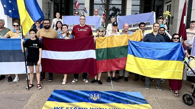 Members of the Latvian, Lithuanian and Ukraine communities stand together in Darwin in front of Northern Territory Parliament House