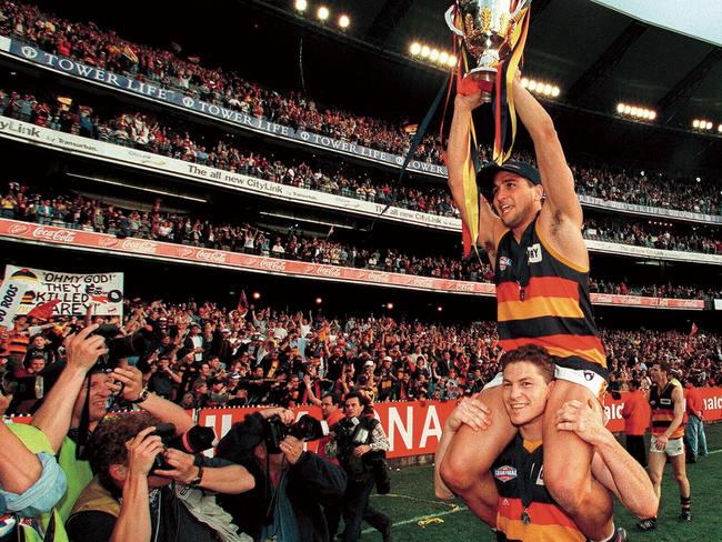 Mark Bickley holds up McLeod with the AFL Grand Final trophy. The Crows defeated North Melbourne at the MCG.