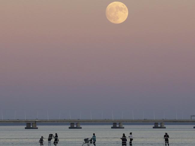 People stroll along the Tagus riverside in Lisbon as the moon rises Sunday, Nov. 13 2016. The so-called Supermoon on Nov. 14, 2016, will be the closest a full moon will have been to Earth since 1948. Picture: AP Photo/Armando Franca