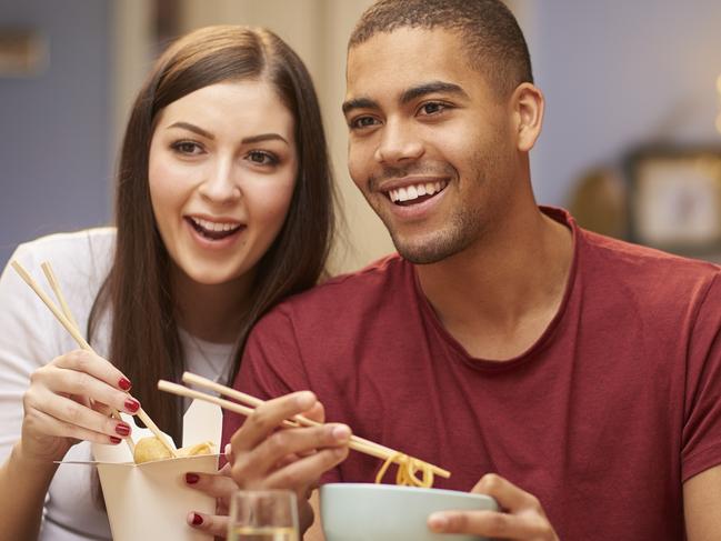 A young couple enjoying takeaway food at home. Picture: iStock.