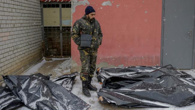 A Ukrainian man in camouflage stands next to snow-covered body bags in the yard of a morgue in Mykolaiv, a city on the shores of the Black Sea that has been under jeavy Russian attack. Picture: AFP