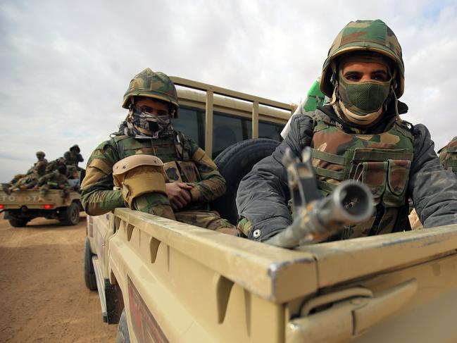 Members of the Iraqi forces and paramilitaries of the Hashed al-Shaabi (Popular Mobilisation units) ride in the back of pickup trucks during the advance through Anbar province, 20 kilometres east of the city of Rawah in the western desert bordering Syria, on November 25, 2017, in a bid to flush out remaining Islamic State (IS) group fighters in the al-Jazeera region. / AFP PHOTO / AHMAD AL-RUBAYE