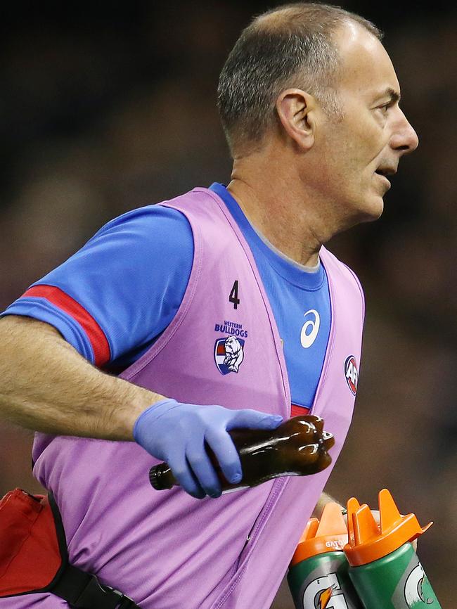 A Western Bulldogs trainer removes the Coke bottle that was thrown. Pic: Michael Klein