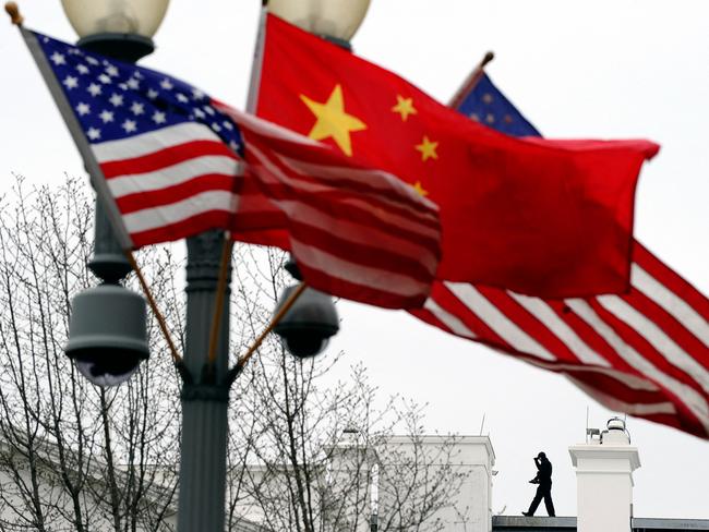 A Secret Service agent guards his post on the roof of the White House as a lamp post is adorned with Chinese and US national flags in Washington, DC.